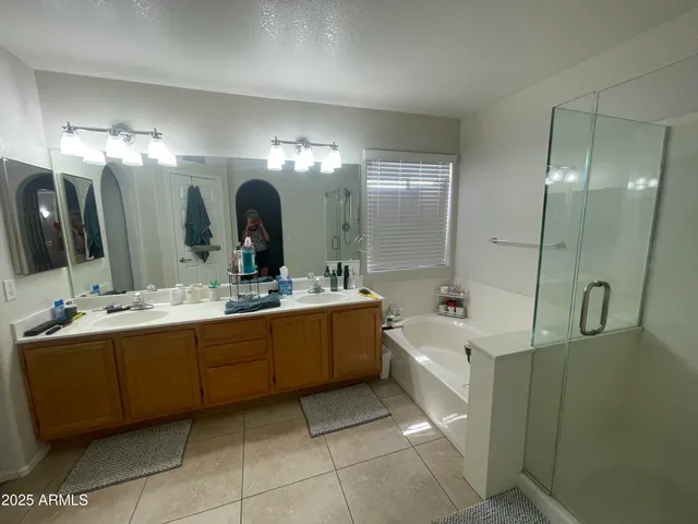 a bathroom with a double vanity sink mirror and bathtub
