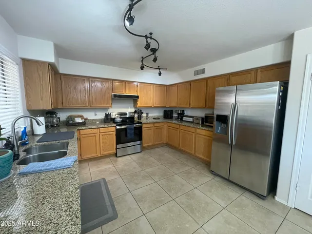a kitchen with stainless steel appliances granite countertop a sink a stove a refrigerator cabinets a sink and a stove