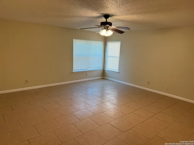 a view of an empty room with a chandelier fan