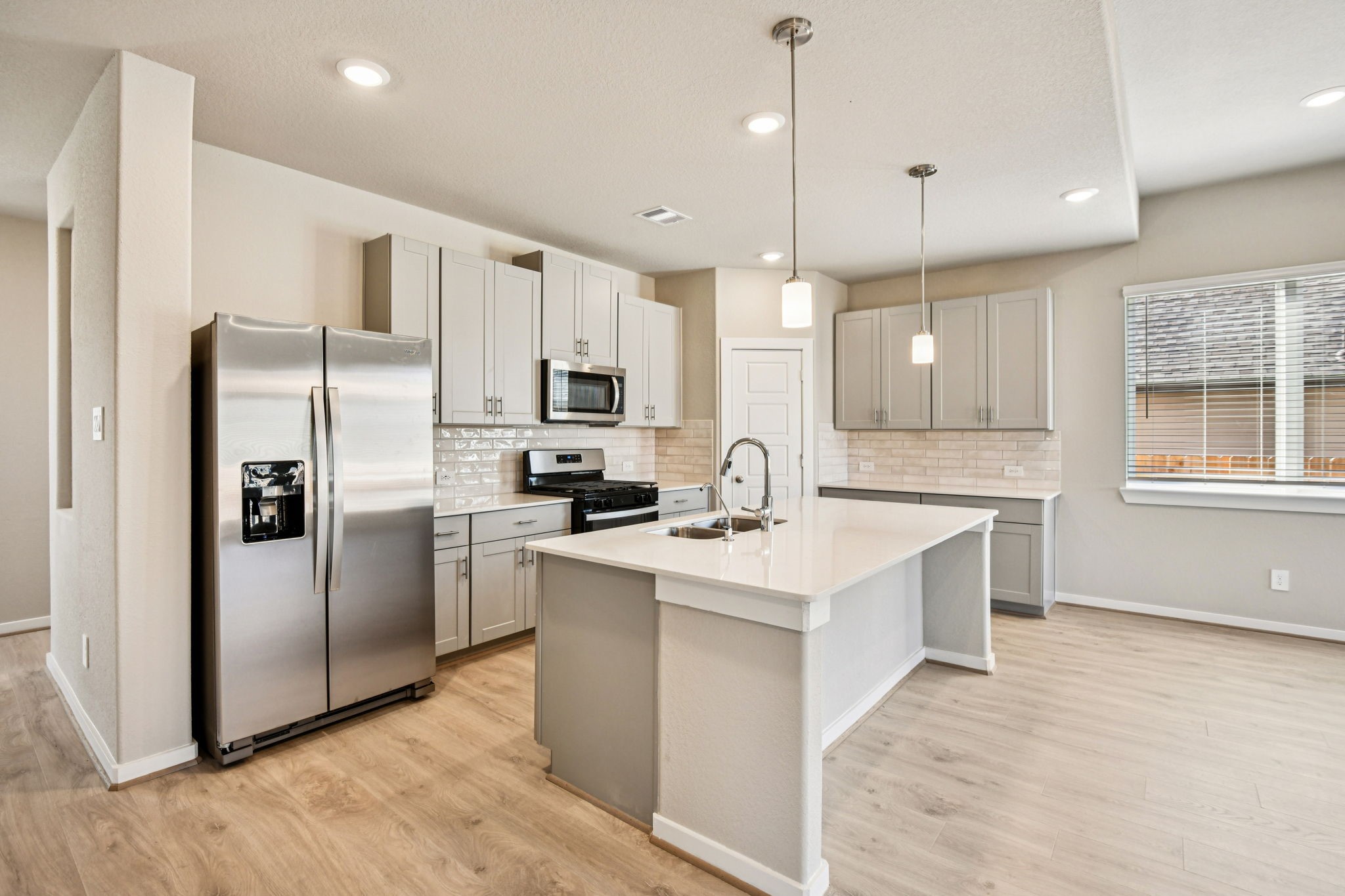 17892 Stone Terrace Montgomery, TX 77316 - Photo 17 of 49 a kitchen with stainless steel appliances kitchen island granite countertop a refrigerator a sink a stove and white cabinets with wooden floor