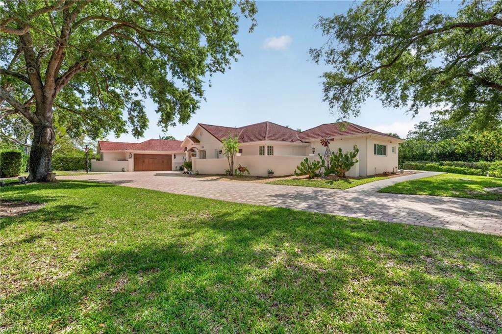 175 Palm River Boulevard Naples, FL 34110 - Photo 3 of 45 a front view of a house with a yard and trees