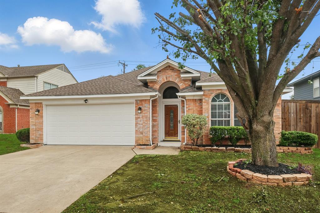 View of front of house featuring an attached garage, driveway, roof with shingles, and brick siding