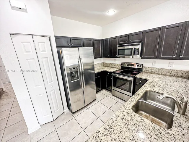 a kitchen with stainless steel appliances a stove a sink and a refrigerator