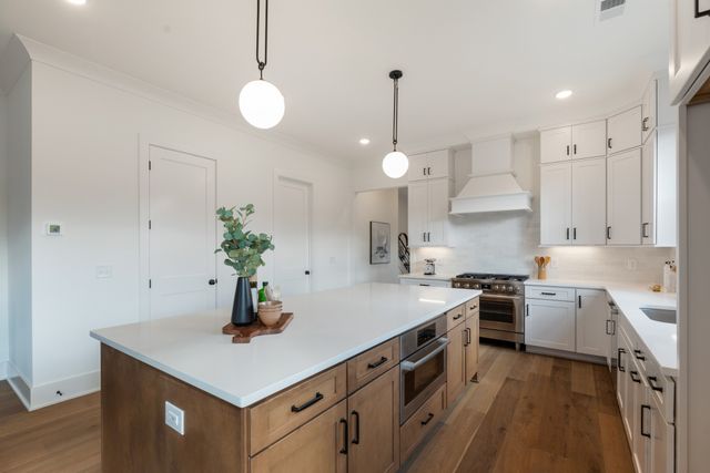 a kitchen with stainless steel appliances a dining table chairs and white cabinets