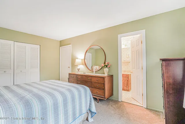 a bedroom with a bed a mirror on dresser and a window