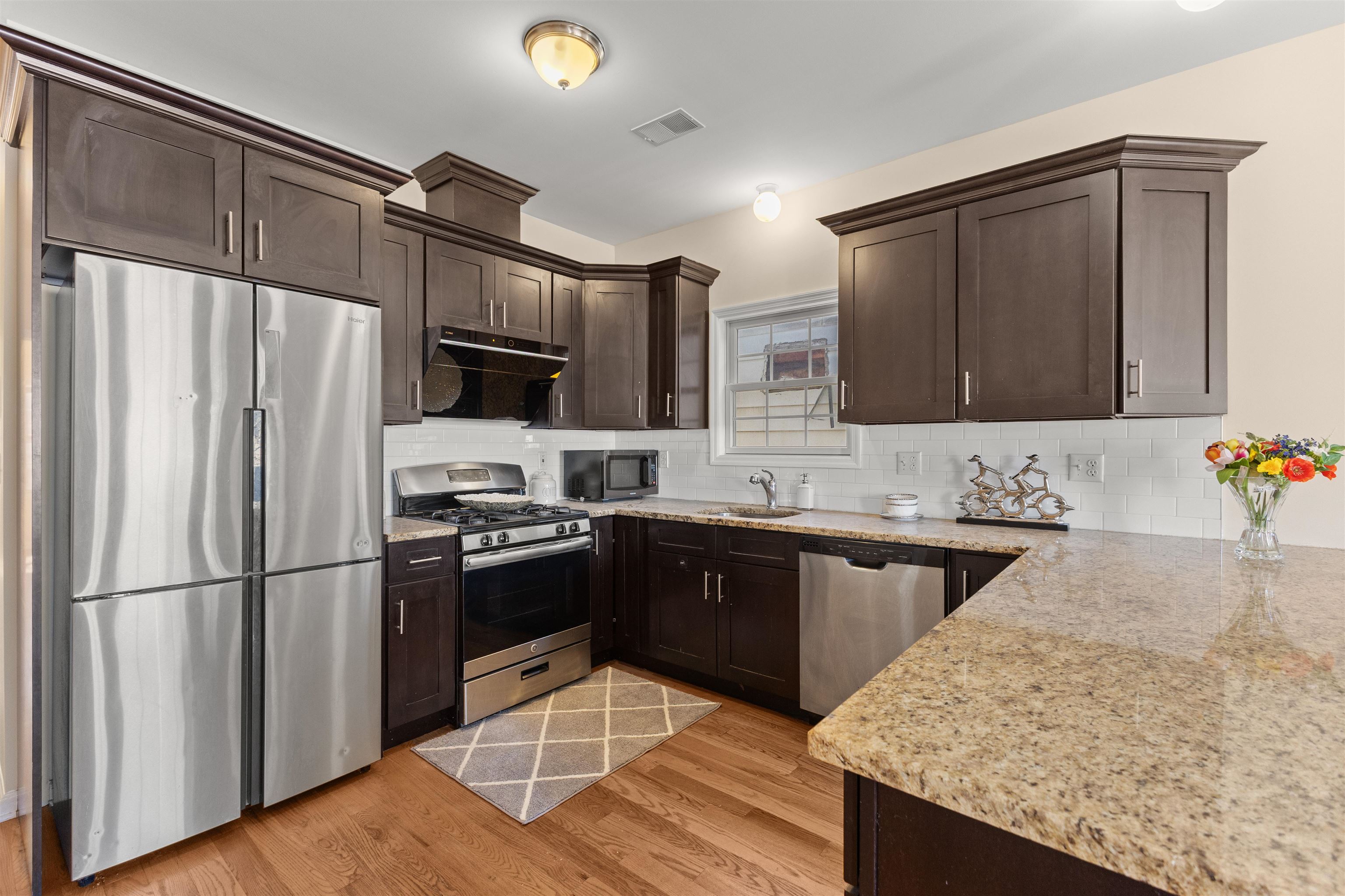 23 Reynolds Avenue, Unit 1 Harrison, NJ 07029 - Photo 3 of 23 a kitchen with granite countertop a refrigerator stove and sink
