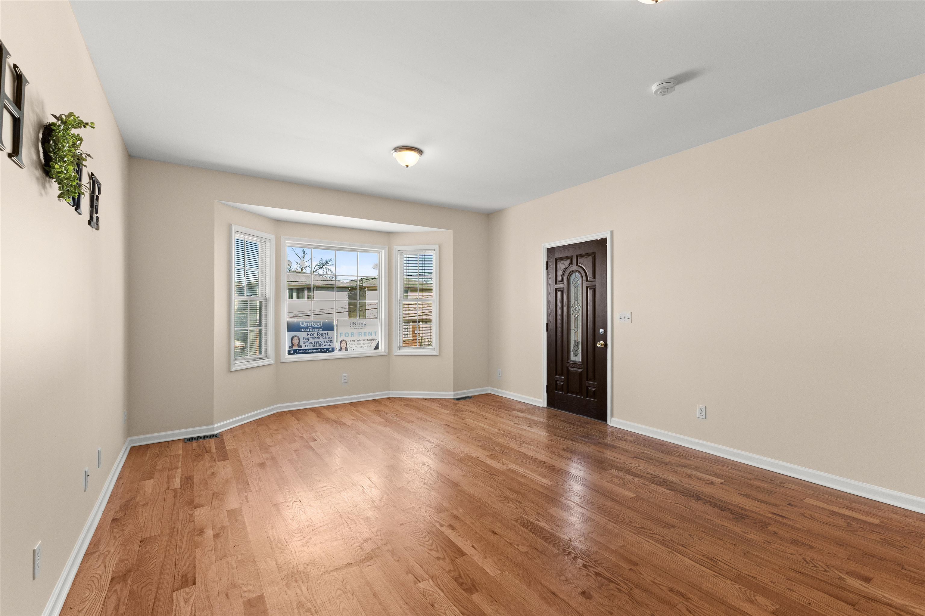 23 Reynolds Avenue, Unit 1 Harrison, NJ 07029 - Photo 6 of 23 a view of an empty room with wooden floor and a window