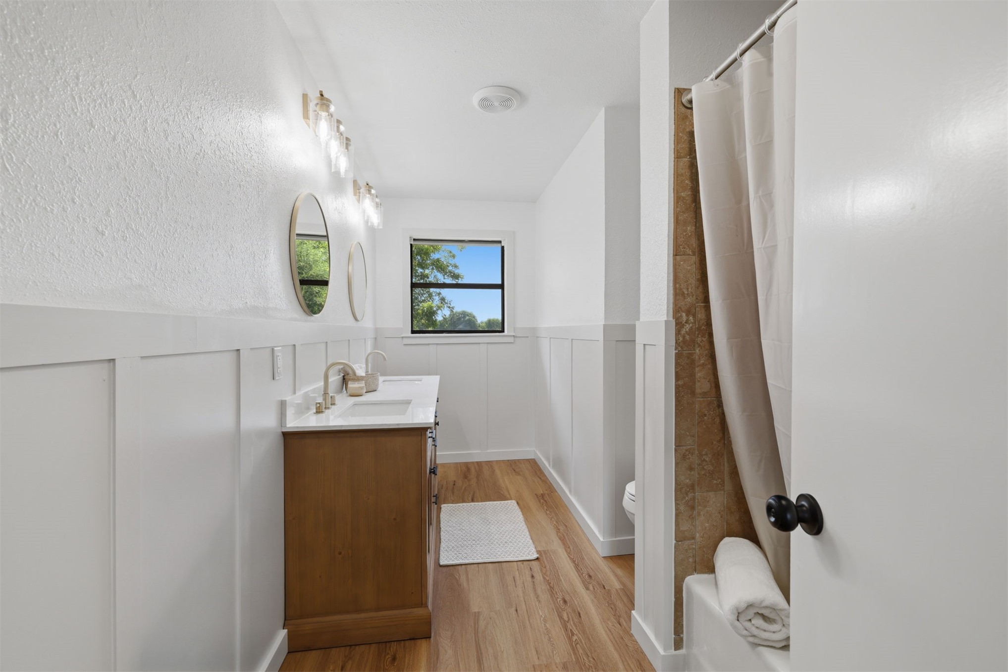 633 Swinney Road Mead, OK 73449 - Photo 12 of 32 Bathroom featuring a wood-finish double vanity with white countertops, dual round mirrors, and brushed nickel fixtures