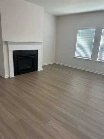 an empty room with wooden floor fireplace and windows