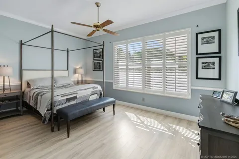 a bedroom with a bed a dresser and potted plants