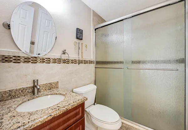 a bathroom with a granite countertop sink a toilet and a mirror