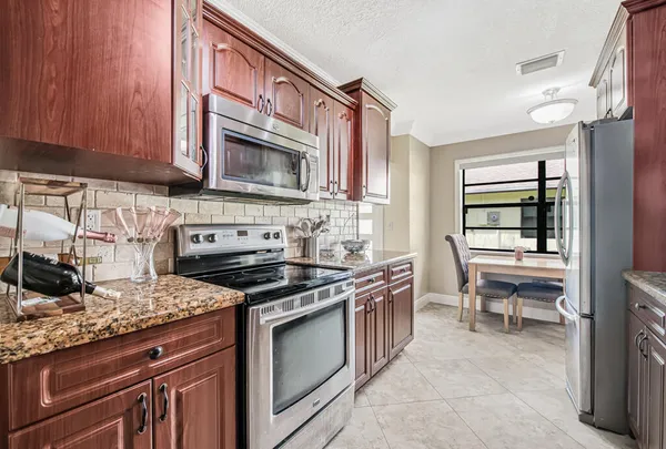 a kitchen with stainless steel appliances granite countertop a stove top oven a sink dishwasher and cabinets with wooden floor