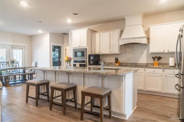 a kitchen with stainless steel appliances granite countertop a stove a sink a microwave a dining table and chairs