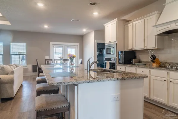 a kitchen with stainless steel appliances granite countertop a stove a sink a dining table and chairs