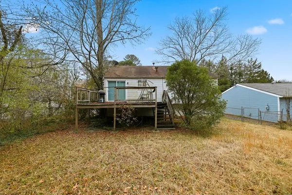 front view of a house with a large tree and a wooden fence