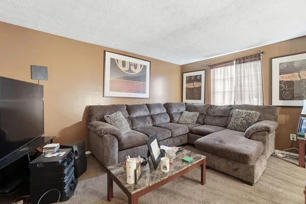 a living room with furniture a flat screen tv and a window