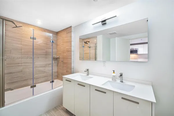 a bathroom with a bathtub shower sink and mirror