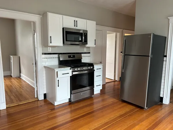 a kitchen with a refrigerator stove and wooden floor