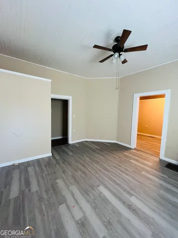 an empty room with wooden floor a ceiling fan and windows