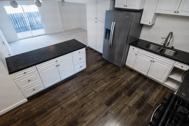 a kitchen with granite countertop white cabinets and refrigerator