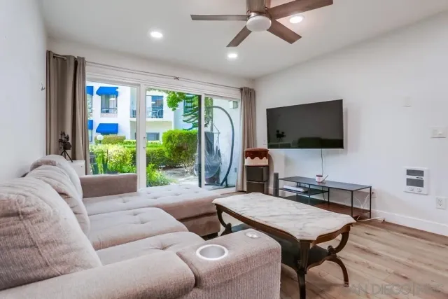 a living room with furniture a flat screen tv and a floor to ceiling window