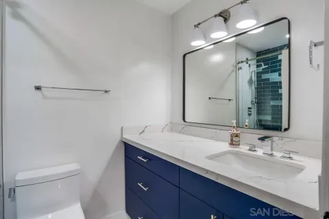 a bathroom with a granite countertop sink a toilet and a mirror