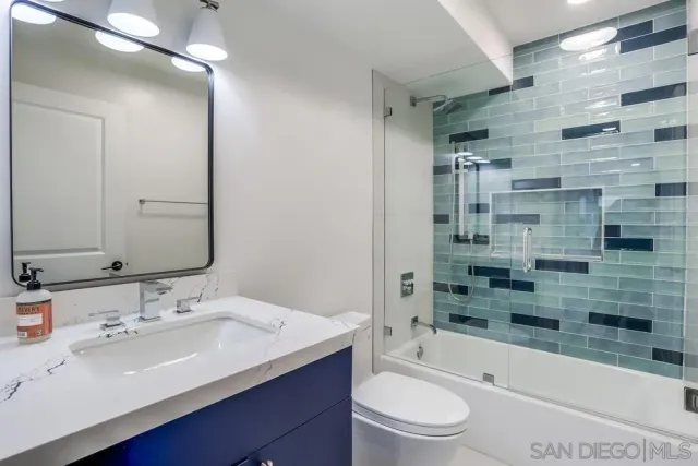 a bathroom with a bathtub shower sink mirror vanity and toilet