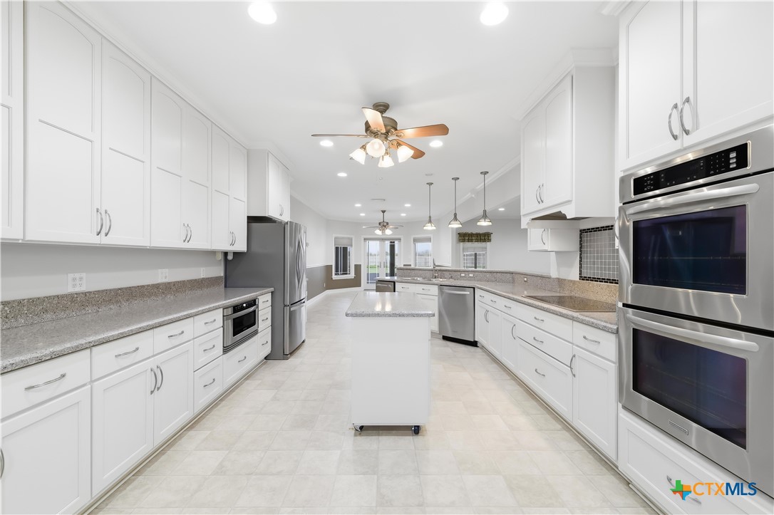 1118 East Maxwell Ditch Road Port Lavaca, TX 77979 - Photo 11 of 36 a large kitchen with cabinets a island a stove a oven a dining table and chairs