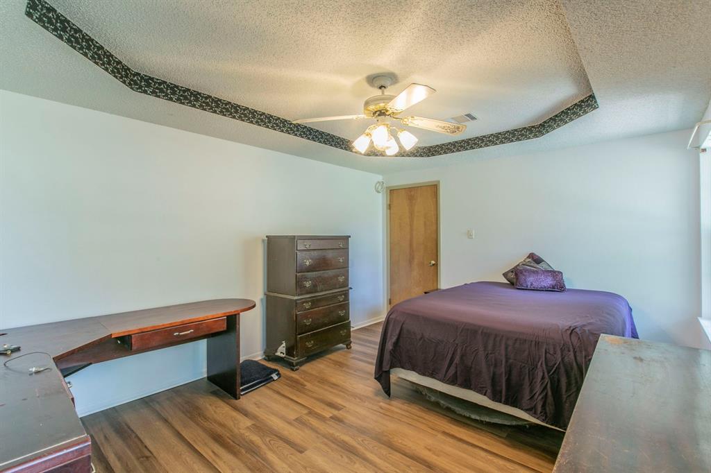 1936 Post Oak Drive Waco, TX 76705 - Photo 16 of 33 Bedroom featuring a textured ceiling, wood finished floors, an office area, ceiling fan, and a tray ceiling