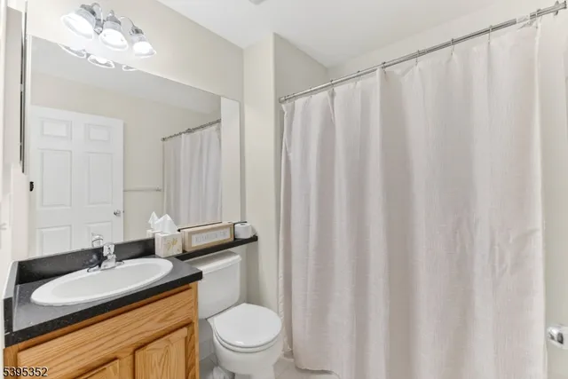 a bathroom with a granite countertop sink toilet and mirror