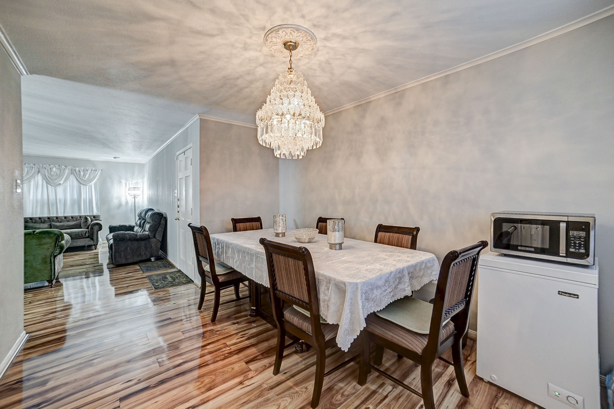 7900 Westheimer Road, Unit 202 Houston, TX 77063 - Photo 13 of 25 Elegant dining area with a stunning chandelier and rich wood flooring, seamlessly connected to a cozy living space filled with natural light.