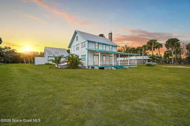 a view of a house with a big yard and large trees