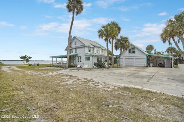 a front view of a house with a yard and ocean view