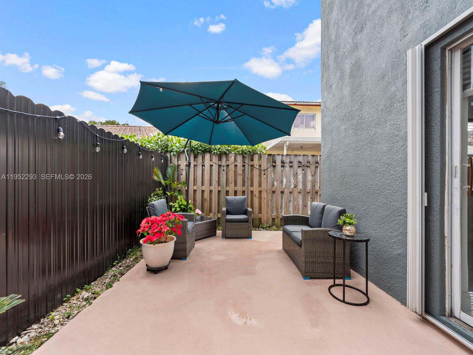 15626 Southwest 100th Terrace Miami, FL 33196 - Photo 7 of 30 a view of a patio with table and chairs under an umbrella with wooden fence