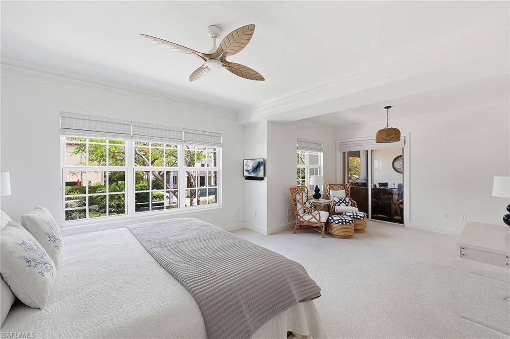 411 6th Street South, Unit 202 Naples, FL 34102 - Photo 20 of 37 a bedroom with a bed a couch and a chandelier