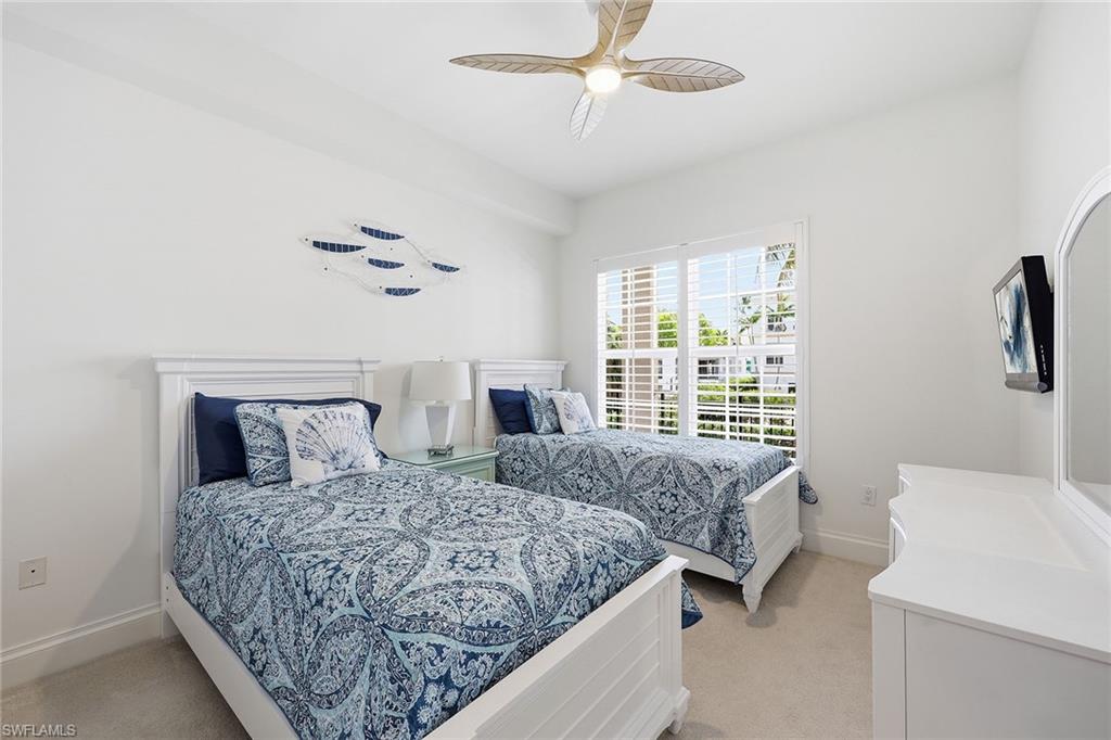 411 6th Street South, Unit 202 Naples, FL 34102 - Photo 26 of 37 a bedroom with a large bed and a chandelier