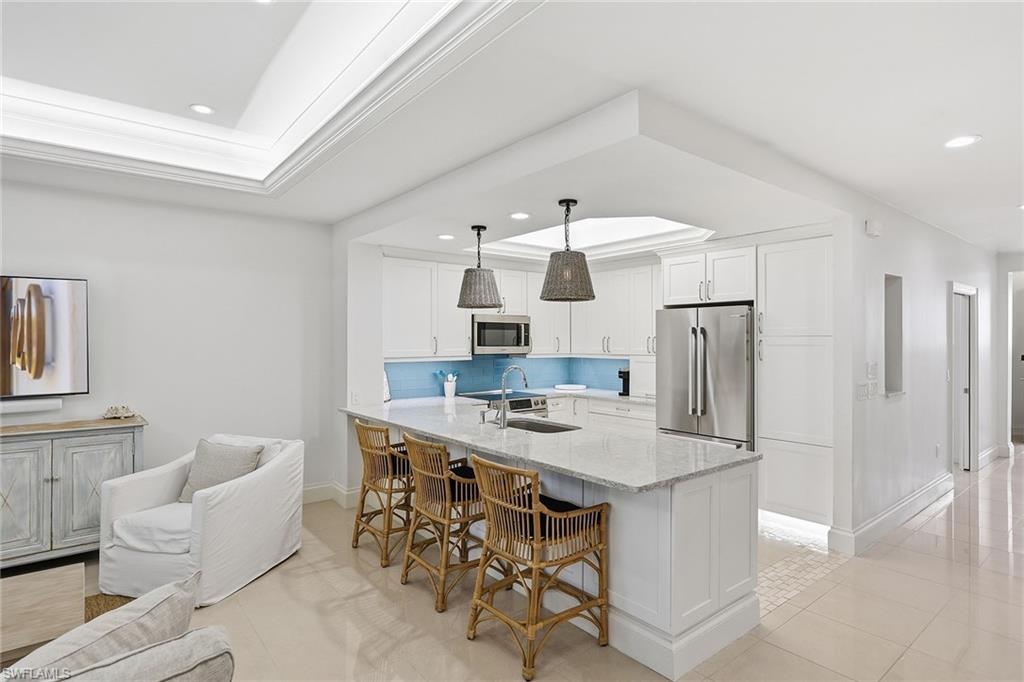 411 6th Street South, Unit 202 Naples, FL 34102 - Photo 8 of 37 a kitchen with stainless steel appliances kitchen island granite countertop a table chairs and a refrigerator
