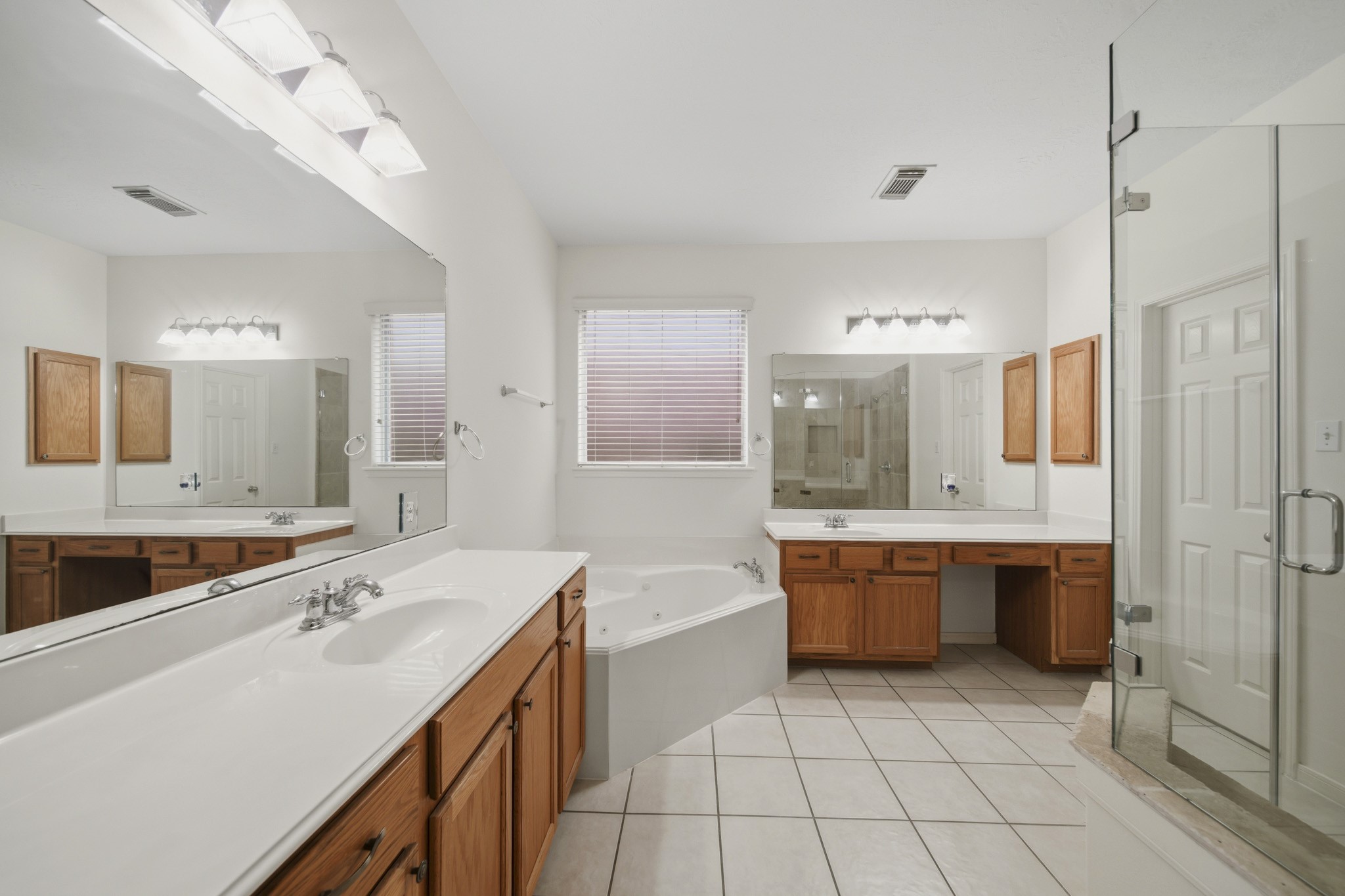 3306 Colleville Sur Mer Lane Spring, TX 77388 - Photo 11 of 30 This spacious primary bathroom offers a true spa-like retreat with an expansive layout, dual vanities, and abundant storage throughout. A luxurious corner soaking tub serves as the centerpiece of the space, perfectly positioned beneath a large window that fills the room with natural light.