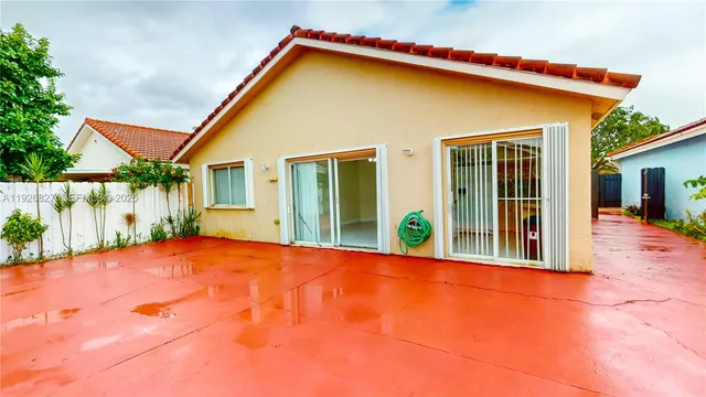a view of yellow house with pool and plants
