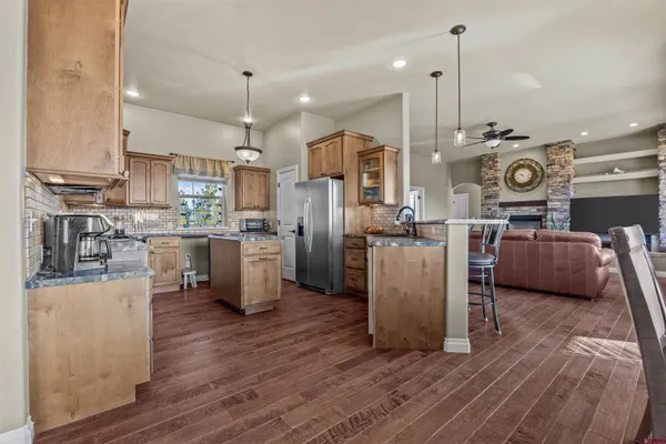 a kitchen with stainless steel appliances granite countertop a sink a stove a refrigerator and island with wooden floor