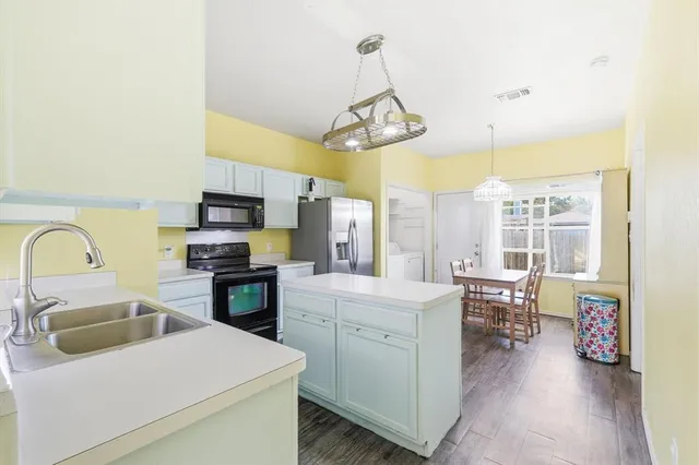a kitchen that has a lot of cabinets a sink and appliances