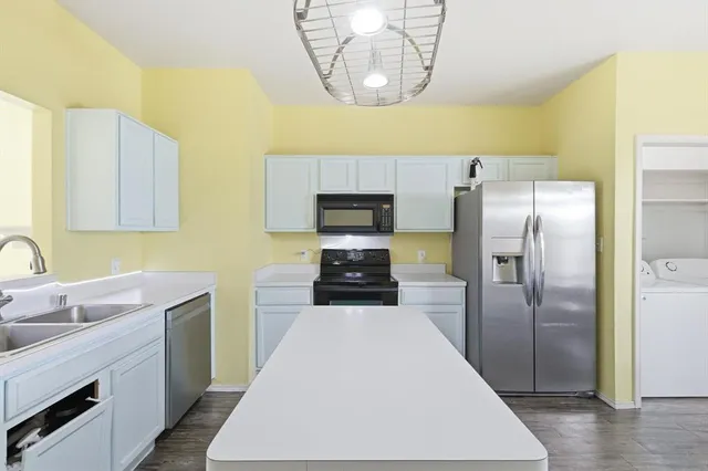 a kitchen with stainless steel appliances a refrigerator a sink a stove and white cabinets