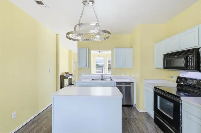 a kitchen with a sink stainless steel appliances and a chandelier
