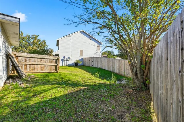 a view of backyard with wooden fence and large trees
