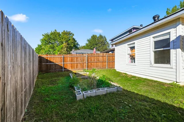 a backyard of a house with plants and wooden fence