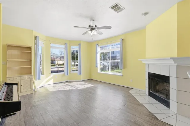 an empty room with windows fireplace and wooden floor