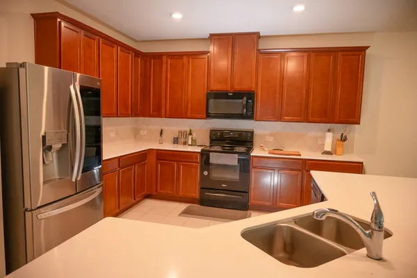 a kitchen with stainless steel appliances granite countertop a refrigerator a sink a stove a microwave and island