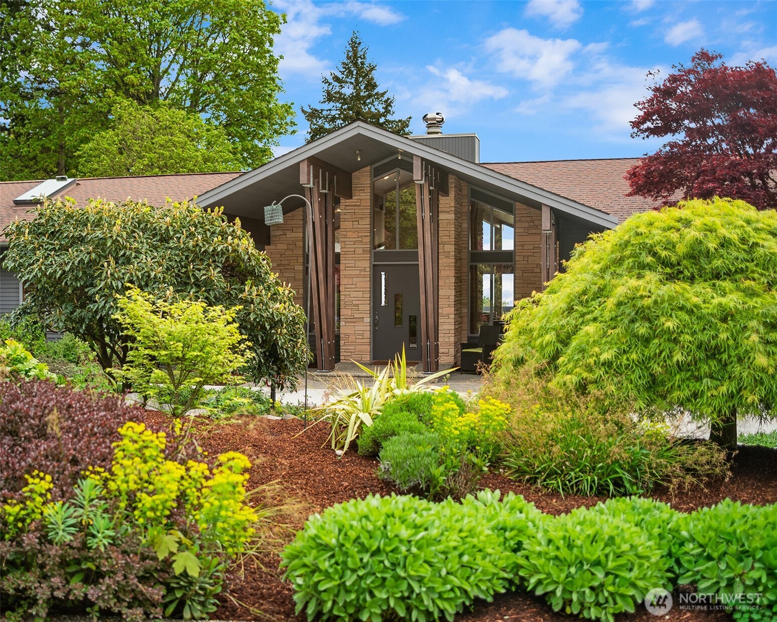 8425 Southwest 216th Street Vashon, WA 98070 - Photo 5 of 40 a yellow house with flower garden in front of it