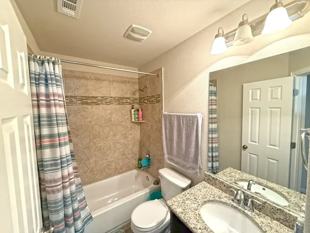 a bathroom with a granite countertop sink toilet bathtub and shower