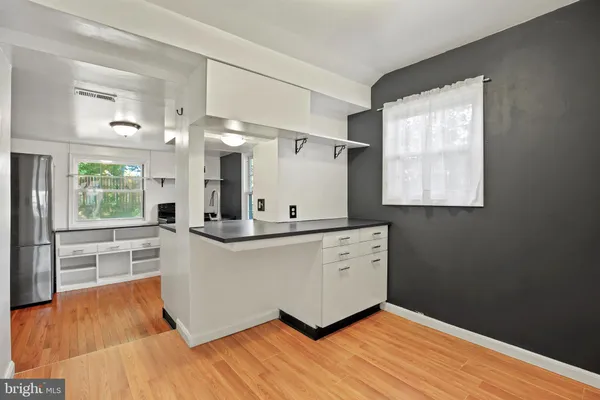 a large white kitchen with kitchen island wooden floors and stainless steel appliances
